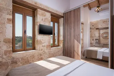 a bedroom with a bed and a tv on a wall at Stella's Traditional House Near the City in SFakianalíon
