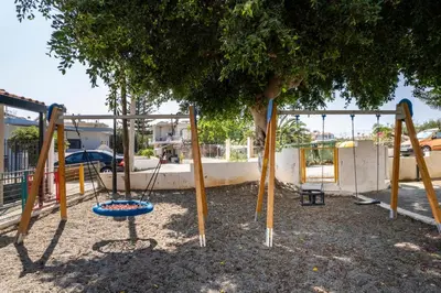 a swing set in a park with a tree at Stella's Traditional House Near the City in SFakianalíon