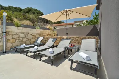 a group of chairs and an umbrella on a patio at Echoes of Prinos in Metókhion Yianítsari