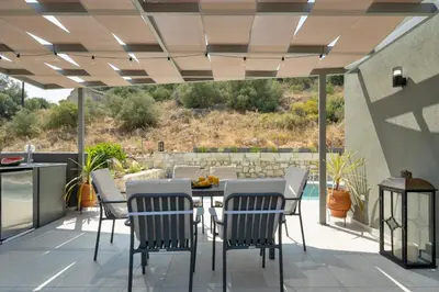 a patio with a table and chairs under a roof at Echoes of Prinos in Metókhion Yianítsari