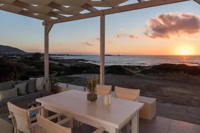 a table and chairs on a patio with a view of the ocean at Falasarna Seafront House I 50m to the Beach in Kavoúsion