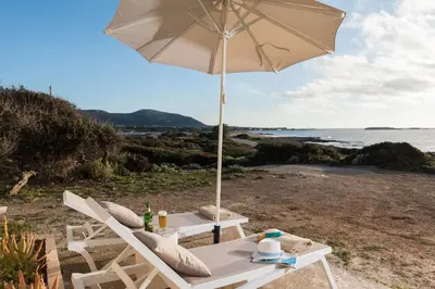 a table and chairs with an umbrella on a beach at Falasarna Seafront House I 50m to the Beach in Kavoúsion
