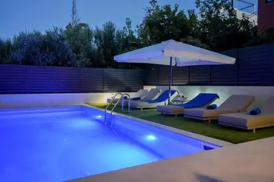 a swimming pool with lounge chairs and an umbrella at Katakis Afroditi-Athina in Agios Onoufrios