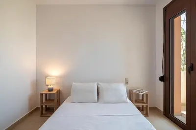 a bed with white sheets and pillows in a room at Light House Chania - 5 Min to Beach and Free Parking in Chania Town