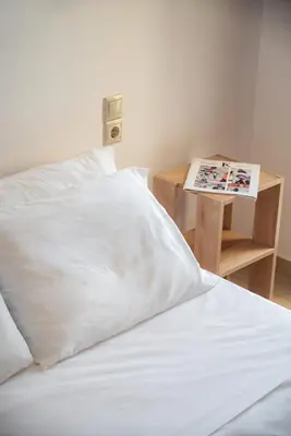 a bed with white sheets and a table with a magazine at Light House Chania - 5 Min to Beach and Free Parking in Chania Town