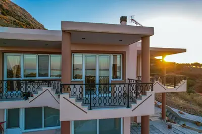 a house with a balcony with a sunset in the background at Elysian Bayview Souda Bay Panorama Chania in Zakhariás