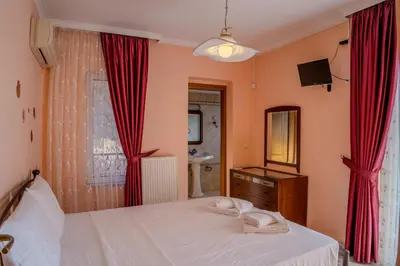 a bedroom with a bed with red curtains and a sink at Elysian Bayview Souda Bay Panorama Chania in Zakhariás