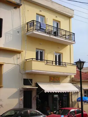 a yellow building with a balcony and cars parked in front of it at Castle Inn in Chania Town