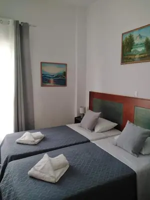 two beds in a hotel room with towels on them at Castle Inn in Chania Town