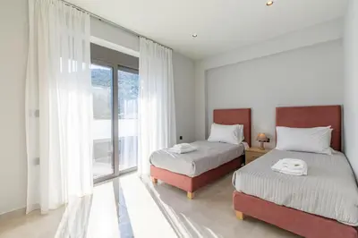 a bedroom with two beds and a large window at Neaira Apartments in Vatólakkos