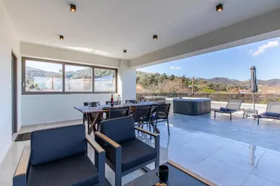 a dining room with a table and chairs and a large window at Neaira Apartments in Vatólakkos