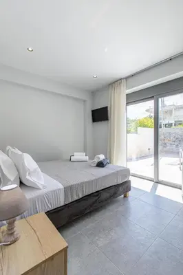 a bedroom with a bed and a large window at Neaira Apartments in Vatólakkos