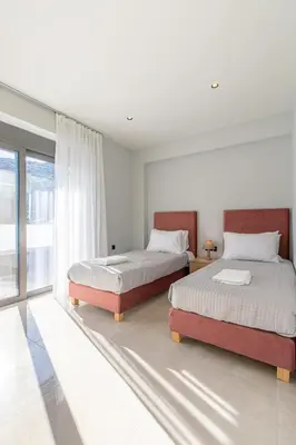 a bedroom with two beds and a large window at Neaira Apartments in Vatólakkos