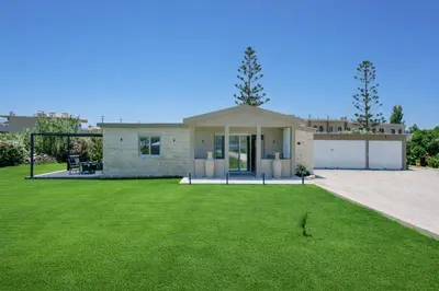 a house with a green lawn in front of it at New Beachfront villa Six Stars in Chania,close to the beach & amenities in Kamisianá