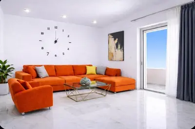 a living room with an orange couch and a clock at New Beachfront villa Six Stars in Chania,close to the beach & amenities in Kamisianá