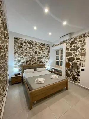 a bedroom with a bed and a stone wall at Armela in Áyioi Theódhoroi