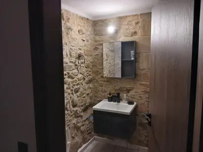 a bathroom with a sink and a stone wall at Stone House Experience in Voúvai