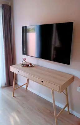 a wooden table with a flat screen tv on a wall at RosaMaria's Garden in Kounoupidhianá