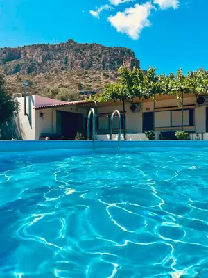 a swimming pool in front of a house with a mountain at Panos Appartments in Palaiochóra