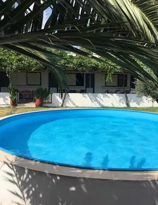 a blue swimming pool in front of a house at Panos Appartments in Palaiochóra