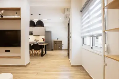 a kitchen and dining room with white walls and wood floors at 2BR Central Chania, Steps to Koum Kapi & Old Town in Chania Town