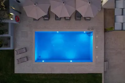 an overhead view of a blue swimming pool with umbrellas at Olea Retreat Villa in Yerakianá