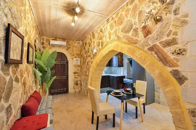 a living room with a table and a stone wall at Villa Ravdoucha in Ravdhoúkha