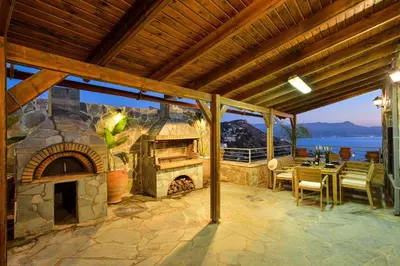 a patio with a stone fireplace and a table and chairs at Villa Ravdoucha in Ravdhoúkha
