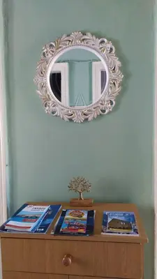 a mirror above a wooden dresser with books on it at Chania ELIA apARTment Chalepa in Chania Town
