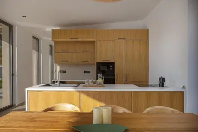 a kitchen with wooden cabinets and a table with chairs at Salisol Villa - Green Oasis in Chania Town