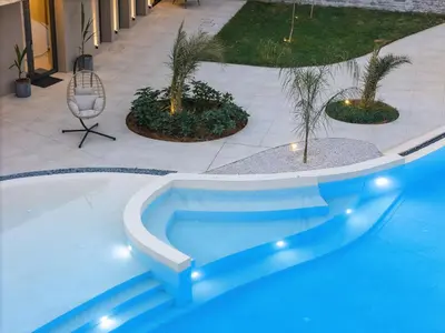 a blue swimming pool with trees in a courtyard at Salisol Villa - Green Oasis in Chania Town