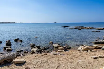 a beach with rocks and water on a sunny day at A to Z in Palaiochóra