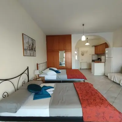 two beds in a large room with a kitchen at Hillside Escape by the Sea in Daratso