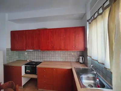 a small kitchen with red cabinets and a sink at Nikolaos central cozy apartment & free parking in Chania Town