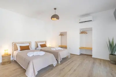 two beds in a room with wooden floors at Roots Villa in Skinés