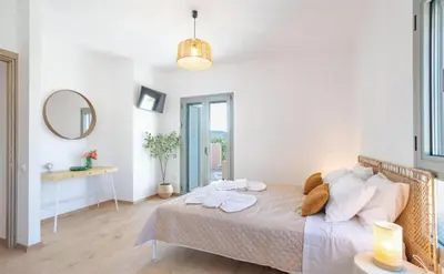 a white bedroom with a bed with towels on it at Roots Villa in Skinés