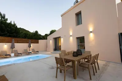 a patio with a table and chairs and a pool at Roots Villa in Skinés