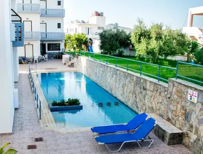 a swimming pool with two lounge chairs on a balcony at Popi Hotel Apartments in Agia Marina Nea Kydonias