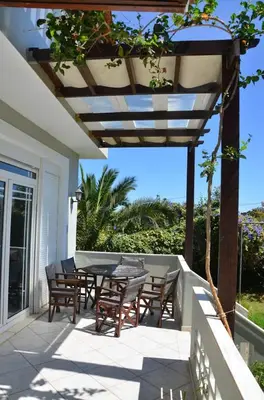 a patio with a table and chairs on a porch at Villa Esperado Gardens Maleme in Maleme