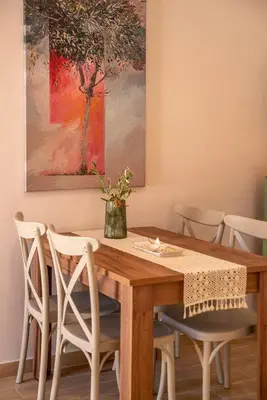 a dining room table with white chairs and a painting at Anamniseis Giorgio Falasarna in Plátanos