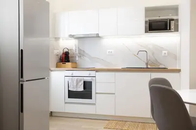 a kitchen with white cabinets and a refrigerator at Chania Moments in Chania Town