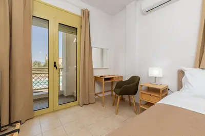 a bedroom with a bed and a desk and a balcony at Sense of Dream Villas in Tavronitis