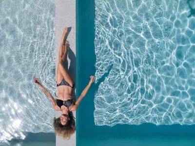 a woman in a bikini floating in a swimming pool at PanStel Twin Villas with private pools and jacuzzi in Ayiá