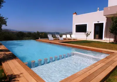 a swimming pool with a deck and a house at Villa Lofos in Perivólia