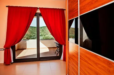 a room with red curtains and a large window at Villa Lofos in Perivólia