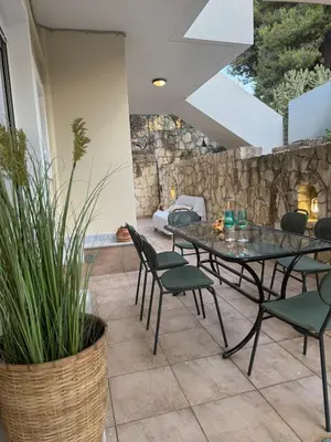 a patio with a table and chairs and a stone wall at Nature spacious apt, 2km from Chania old town, private parking in Chania Town
