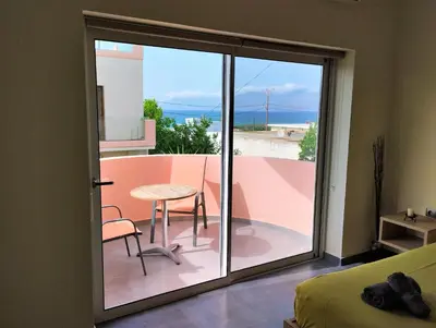 a room with a sliding glass door with a table and chair at Callista sea view or garden in Kissamos