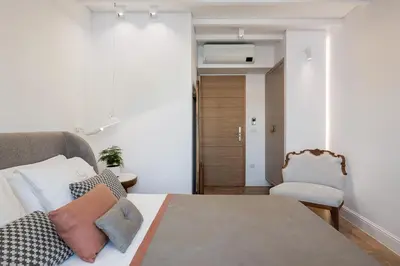 a bedroom with a bed with pillows and a chair at Ionas Boutique Hotel in Chania Town