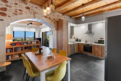 a kitchen and dining room with a wooden table and yellow chairs at Villa Enid in Sinoikismós Mamounianá