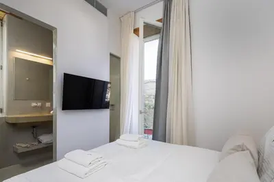 a bedroom with a bed with a tv and a window at Hub Hospitality in Chania Town